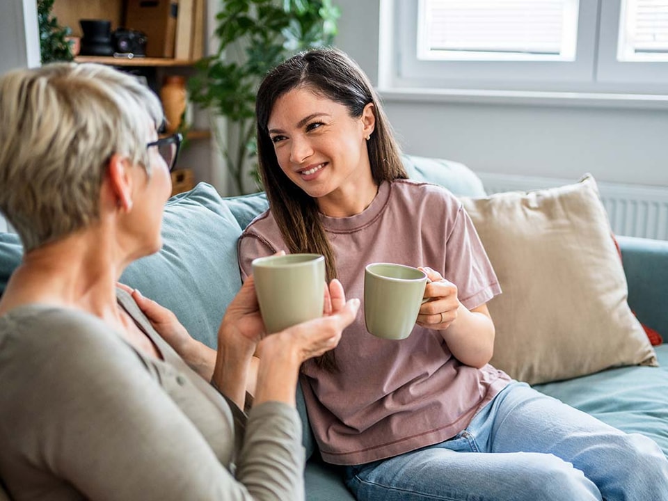 To kvinner sitter i en sofa og drikker kaffe, i forbindelse med hvordan hjelpe barna inn på boligmarkedet