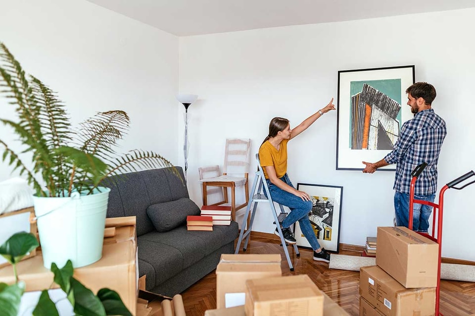 Ungt par har kjøpt bolig sammen og henger opp bilder, illustrasjon til  kjøpe bolig